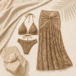 Bikini e gonna lunga all'uncinetto color kaki su tessuto chiaro accanto a una pietra e una conchiglia