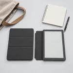 Vue de dessus d'un folio pour liseuse près d'un carnet à spirale, d'un stylo et d'un sac