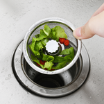 Sink basket lifted above the drain opening with collected scraps visible inside