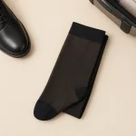 Folded black knee-high socks beside a black shoe and the edge of a suitcase