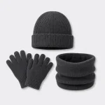 Dunkelgraue Strickmütze über Handschuhen und Schlauchschal in einer flachen Anordnung