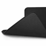 Corner of a black desk pad lifted to reveal the textured underside and stitched border