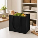 Sac cabas noir contenant du pain et des produits frais sur un plan de cuisine