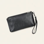 Black leather wristlet clutch at an angle, with centre stitching, a silver-tone zip and wrist strap on beige.