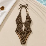Maiô frente única com estampa de leopardo ao lado de uma toalha e óculos de sol perto de uma piscina