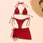 Bikini rosso con bordo leopardato e gonnellina corta accanto a un cappello di paglia e occhiali da sole
