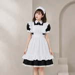 Adult model wearing the short black puff-sleeve maid dress, white ruffled apron and white fabric headpiece against a stone wall.