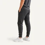 Vue arrière en angle d’un jogger foncé porté avec un haut foncé et des baskets blanches