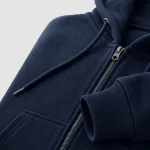 Primo piano di una felpa blu navy con cerniera, coulisse del cappuccio, polsino a coste e cucitura della tasca