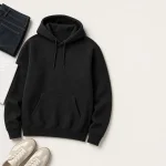 Sudadera negra con capucha extendida junto a vaqueros, top blanco y zapatillas claras