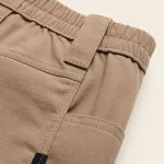 Grande plano de calças de trabalho bege mostrando tecido franzido na cintura, costuras e bolso lateral