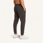 Rear three-quarter view of dark gray joggers worn with white sneakers