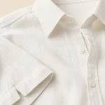 Primo piano di camicia bianca con colletto, bottoni, orlo della manica e trama del tessuto