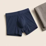 Boxer aderenti blu navy distesi accanto a un asciugamano grigio piegato