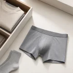Boxers cinzentos estendidos junto a uma gaveta aberta, roupa dobrada e meias cinzentas