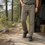 Man wearing olive cargo trousers and black boots outside a cabin