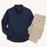 Camisa azul marino con cuello mao extendida junto a pantalones beige doblados
