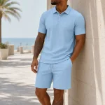 Uomo con polo azzurra e shorts coordinati accanto al muro di una terrazza sul mare