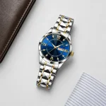 Blue-dial wristwatch laid flat beside a brown wallet and striped fabric.