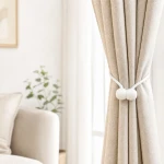 White cord tieback wrapped around a beige curtain with its two rounded ends at the front