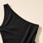 Primo piano di abito nero con scollo asimmetrico, spallina larga e cuciture
