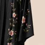 Nahaufnahme von rosa Blumen und grünen Blättern neben dem weiten Ärmel einer schwarzen Abaya