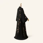 Seiten- und Rückansicht einer schwarzen Blumen-Abaya an einer Schaufensterpuppe mit lang drapiertem Rücken
