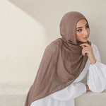 Mulher usando lenço taupe na cabeça e sobre uma blusa branca