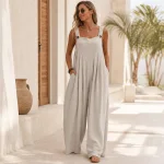 Woman wearing a light gray wide-leg jumpsuit on a terrace with one hand in a pocket
