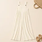 Ivory wide-leg jumpsuit laid flat beside a woven bag and sandals