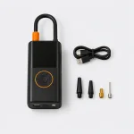 Vista dall’alto di un gonfiatore per pneumatici nero, cavo USB arrotolato e quattro adattatori per ugelli.