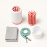 Copo para limpar patas junto de um encaixe de cerdas rosa, uma peça branca em forma de copo, toalha dobrada e trela