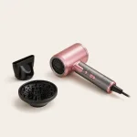 Pink hair dryer laid diagonally beside its separate black nozzle and diffuser.