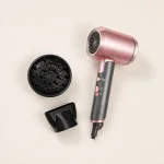 Overhead view of a pink hair dryer with a round diffuser and concentrator nozzle.