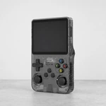Transparent-schwarze Handheld-Konsole auf grauer Tischfläche mit sichtbarem Display und vorderen Bedienelementen