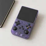 Violette Handheld-Konsole mit ausgeschaltetem Display schräg auf einem hellen Tisch neben einem dunklen Notizbuch