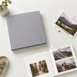 Overhead arrangement of a closed gray album, loose prints and an open photo spread