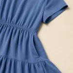 Nahaufnahme eines blauen Kleides mit kurzem Ärmel, geraffter Taille, Seitentasche und Stufennaht