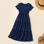 Marineblaues Maxikleid mit kurzen Ärmeln, flach neben einem Strohhut und Sandalen ausgelegt