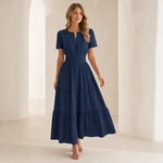 Modelo con el vestido azul marino escalonado en un entorno arquitectónico claro