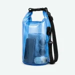 Bolsa azul transparente enrollable, con correa negra y una toalla doblada visible en el interior.