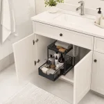 Black two-tier organizer with the lower basket pulled out inside a bathroom vanity cabinet