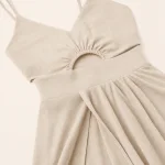 Close-up of an ivory dress with a gathered bodice, curved waist cutout and wide waistband