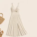 Ivory cutout maxi dress laid flat beside a woven bag and sandals