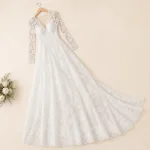 Abito da sposa bianco in pizzo su una gruccia, con gonna e strascico aperti accanto ai fiori