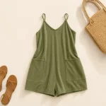Olive short romper laid flat beside a woven bag and sandals