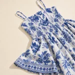 Dettaglio dell'abito blu e bianco con spalline sottili, corpino arricciato e piega dell'orlo decorata