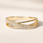 Un anello color oro su ceramica beige, visto frontalmente da un angolo basso, con una fascia di pietre e una curva lucida.