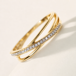 Un anello color oro visto di lato in diagonale, con la curva della fascia e il profilo dell'unica banda di pietre.