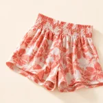 Close-up of the gathered waistband, floral fabric and leg openings of coral shorts